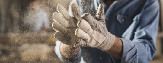 Close up of dusty work gloves Unrecognizable male hands with work gloves on, clapping to remove sawdust